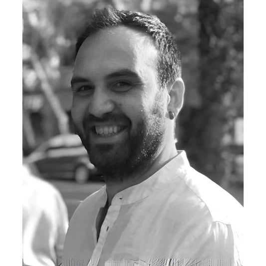 Uomo sorridente con capelli corti scuri e barba in camicia chiara per servizio consulenza restauro dario arredamento vintage