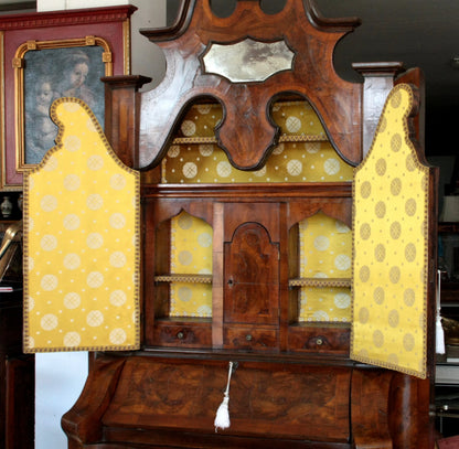 Trumeau lombardo originale in noce con linea trapezoidale elegante e corpo mosso presenta scaffali aperti rivestiti in tessuto giallo