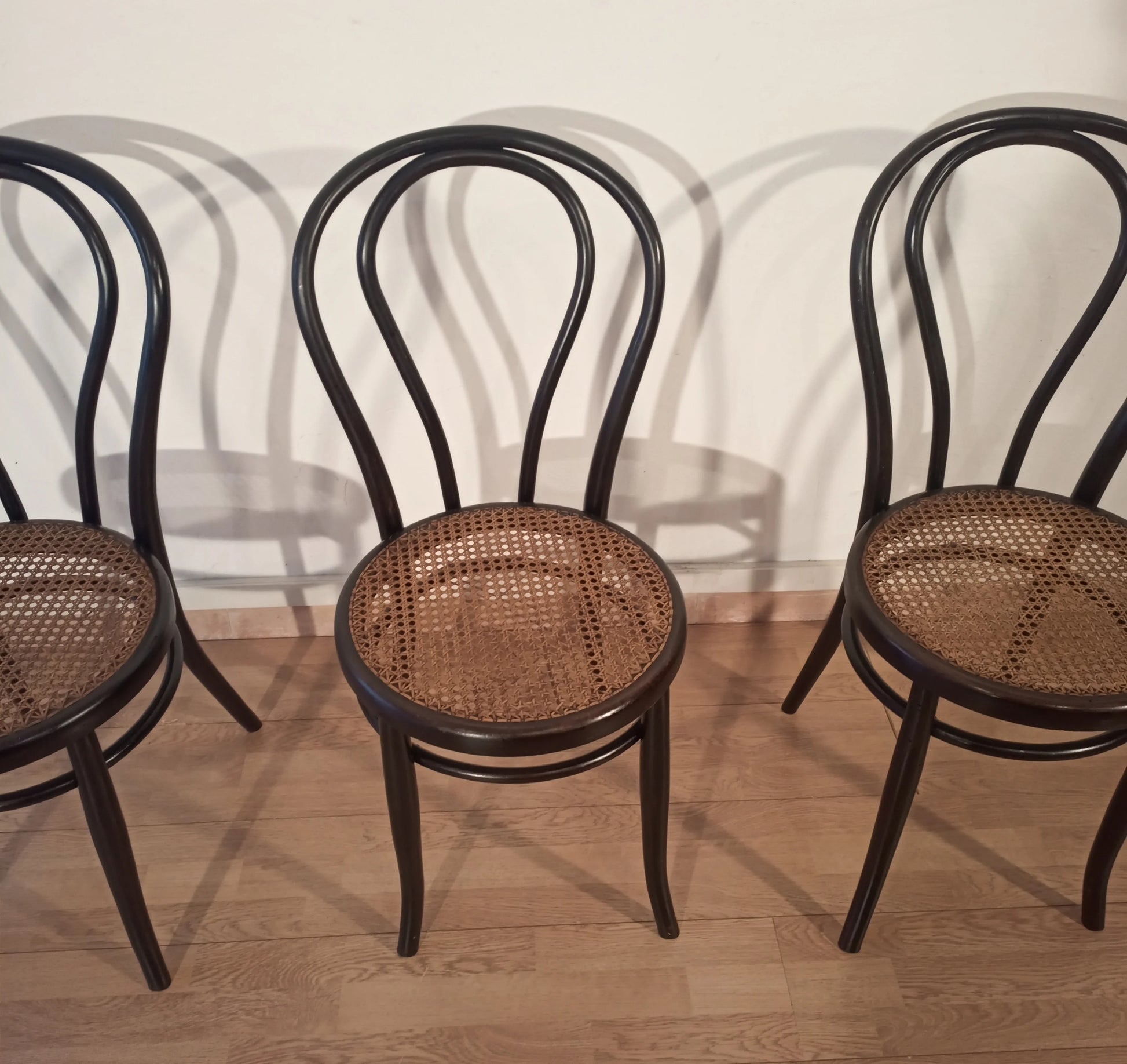Tre sedie nere in faggio curvato con sedili in vimini nello stile thonet italia set, disposte in fila