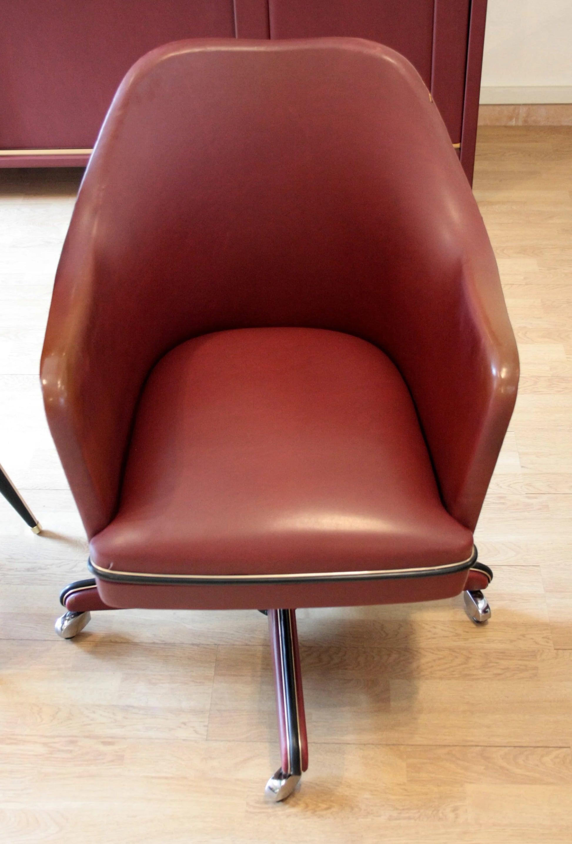 Sedia swivel bordeaux in pelle nel set studio umberto mascagni con scrivania ministeriale disegnata italia 1950
